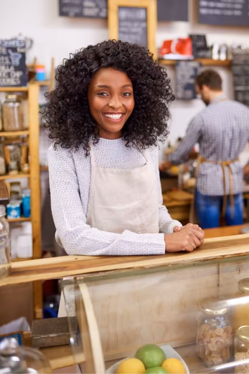 Small business owner smiling behind a shop counter