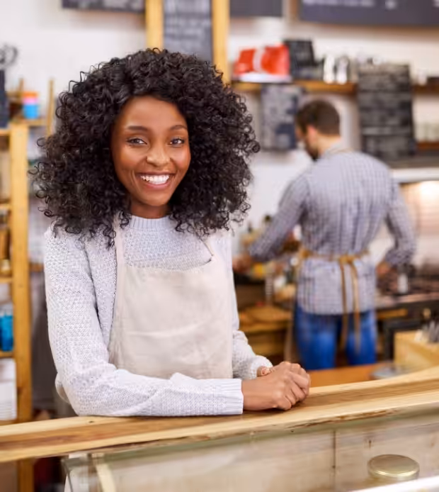 Small business owner smiling behind a shop counter